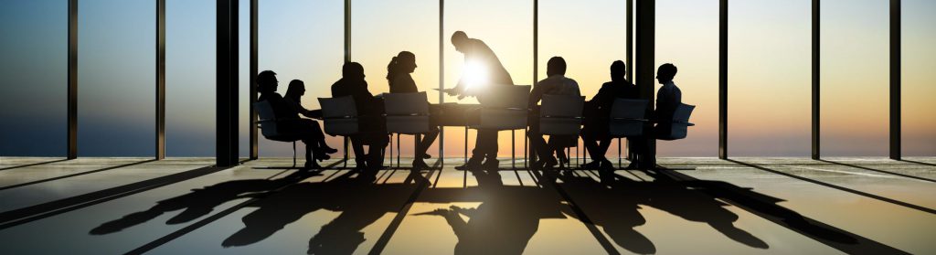 Group of business around the conference table with a view of sunset.