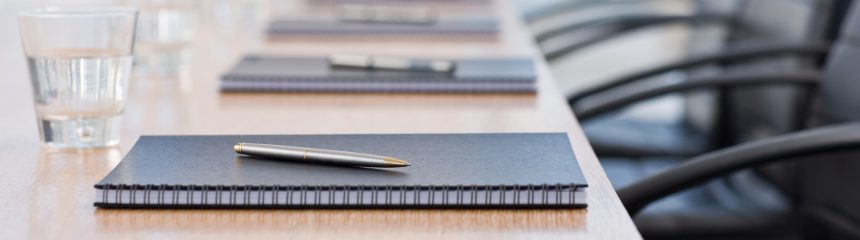 Closeup of notepad kept on table in empty conference room